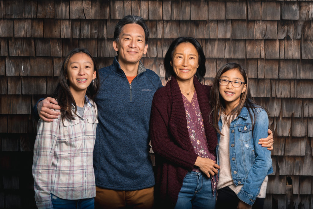 family in front of barn wearing neutral colors for family photo session 