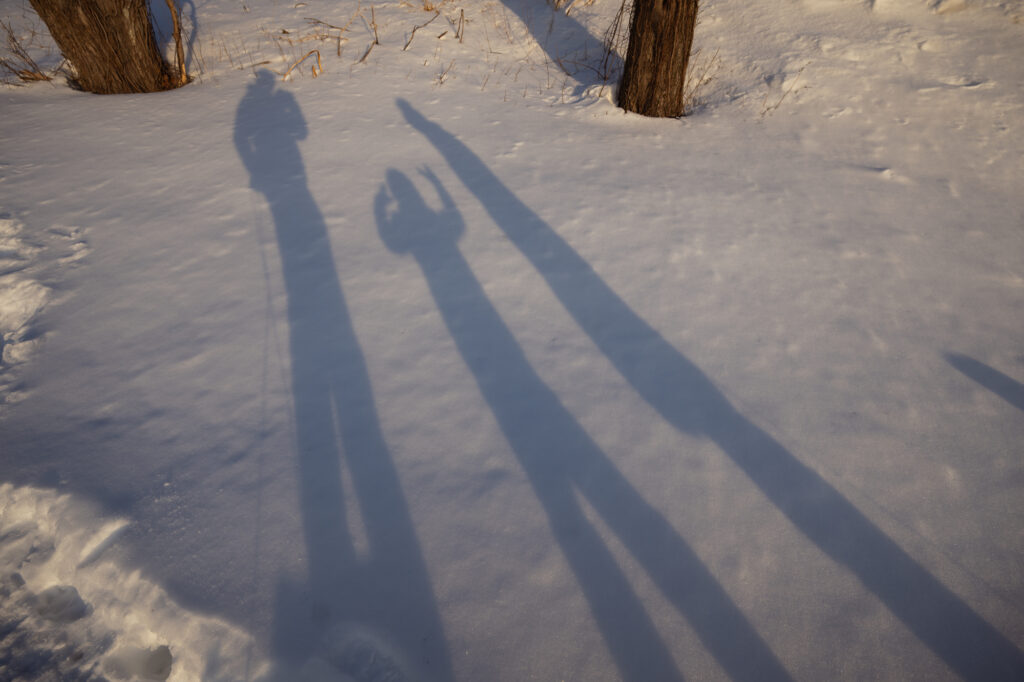 Long shadows of family on snow during winter afternoon family photography session in Lincoln Massachusetts - Corey Flint Photography