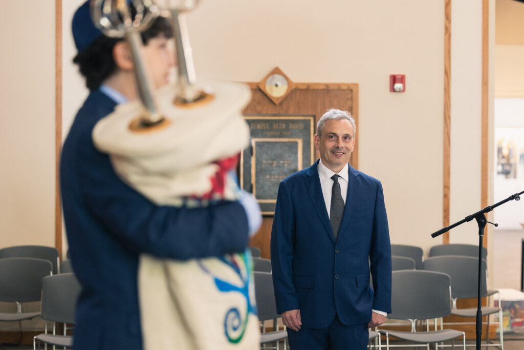 Father watching his son carry the Torah scroll during bar mitzvah ceremony
