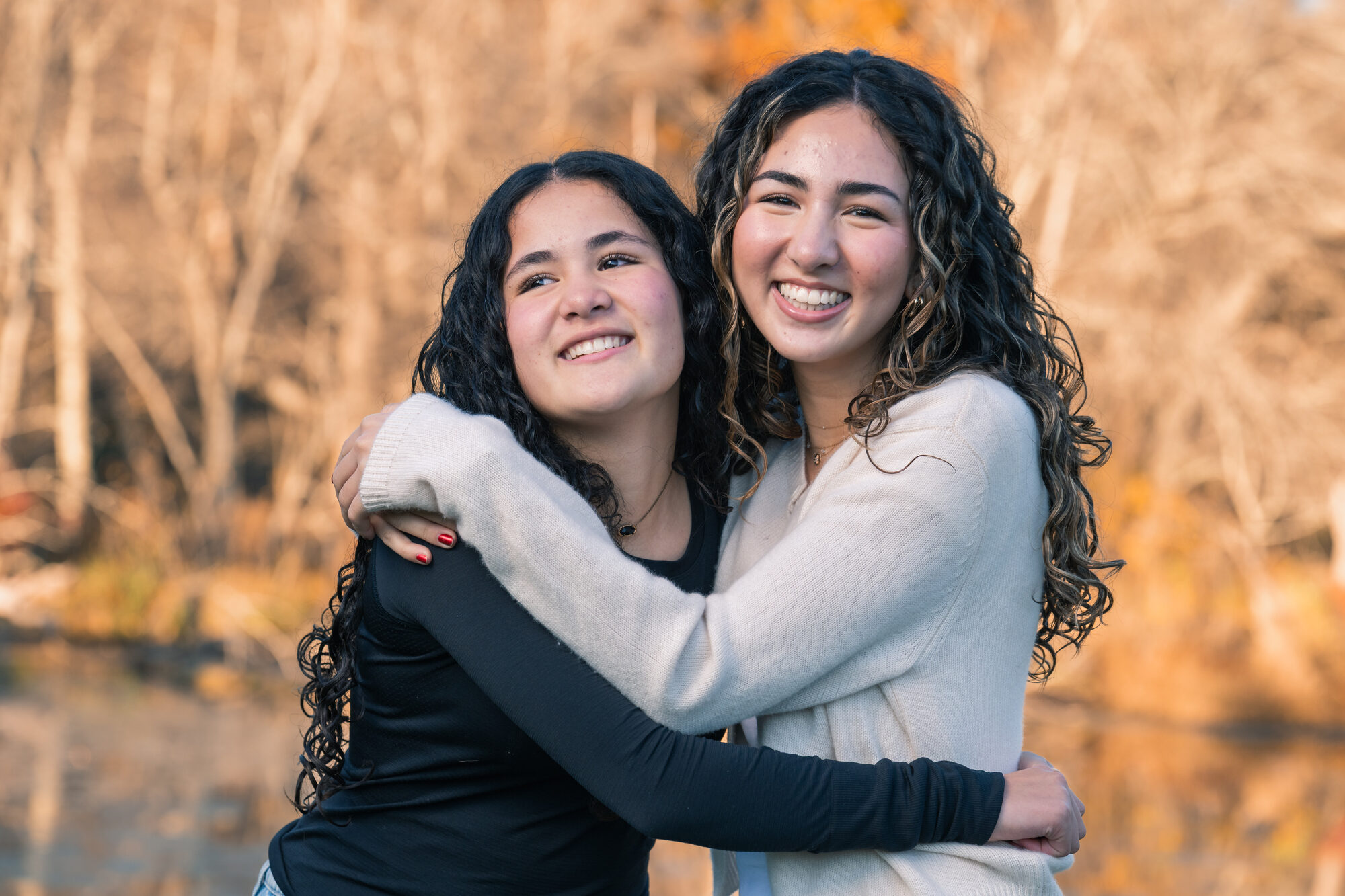 Two sisters hugging and smiling in warm golden autumn light
